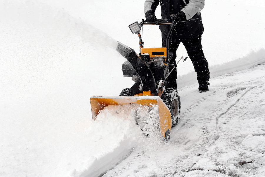 Eine Person räumt Schnee von dem Gehweg